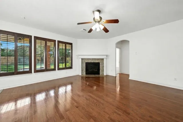 a view of an empty room with wooden floor fireplace and a window