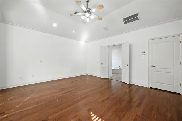 an empty room with wooden floor fan and windows