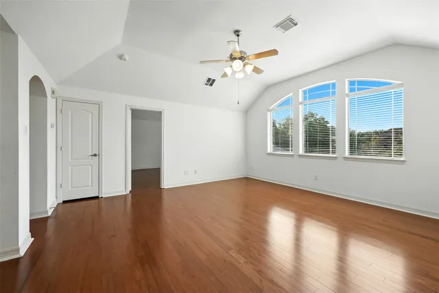 an empty room with wooden floor chandelier and windows