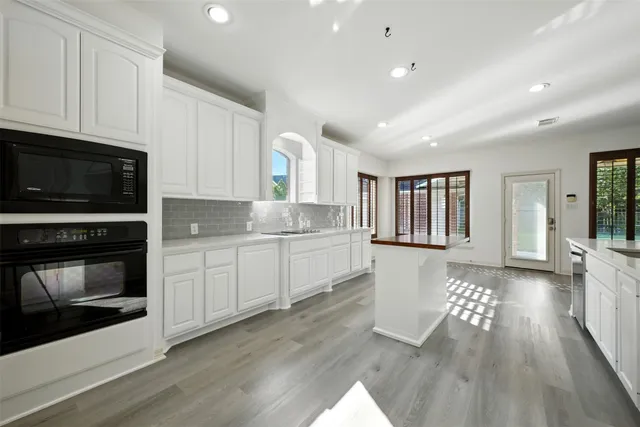 a kitchen with white cabinets and a window
