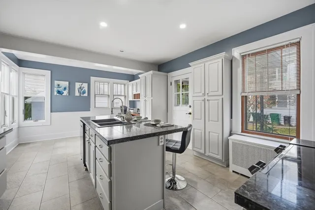 a kitchen with a stove a refrigerator a sink and white cabinets with wooden floor