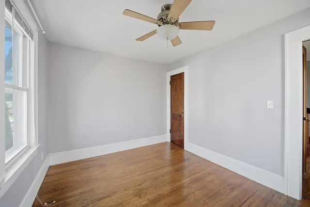 an empty room with wooden floor fan and windows