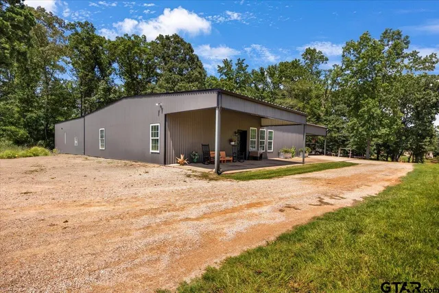 a view of a house with backyard and trees
