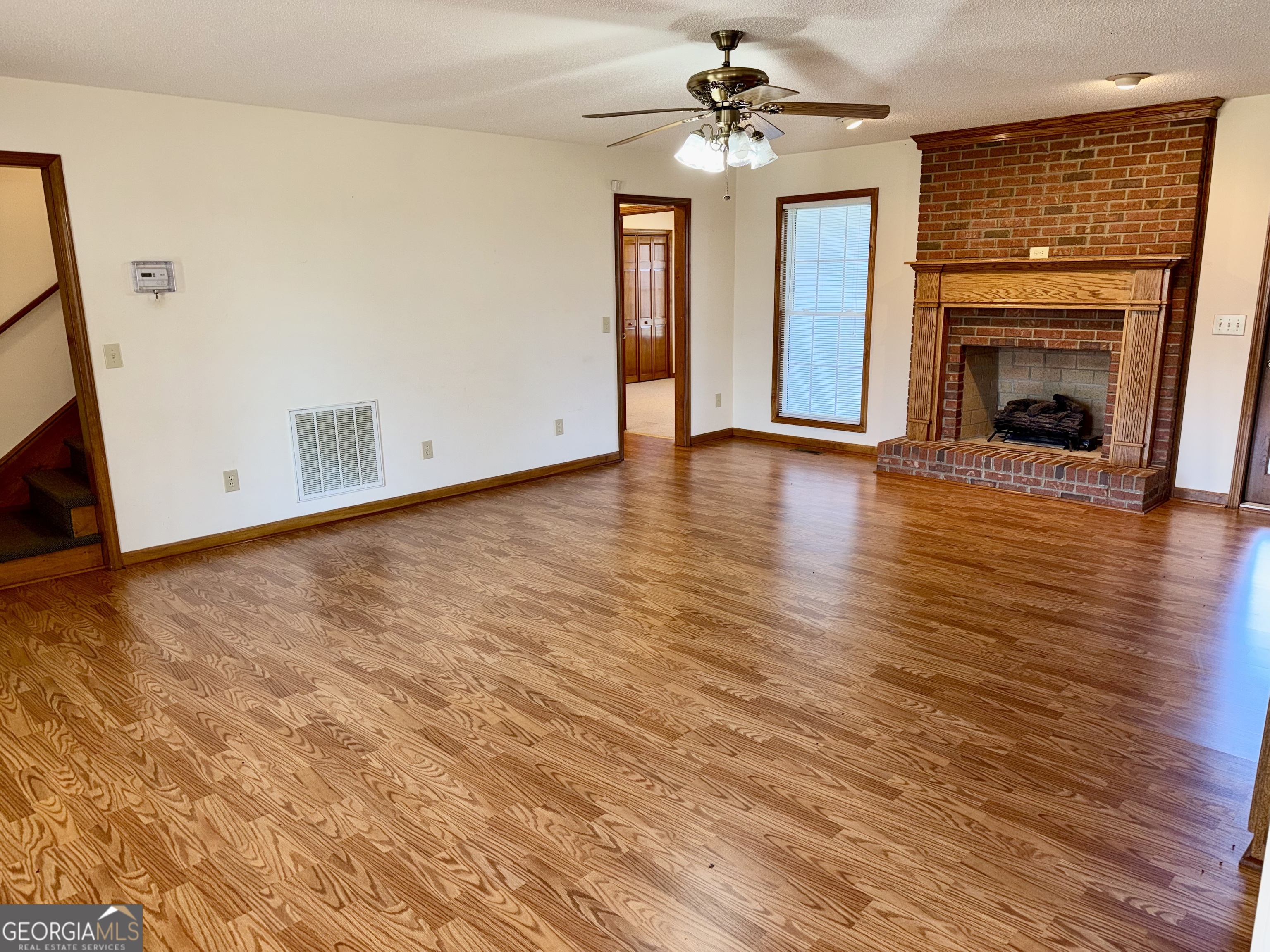 494 Broad Street Bowman, GA 30624 - Photo 15 of 65 wooden floor in an empty room with a fireplace