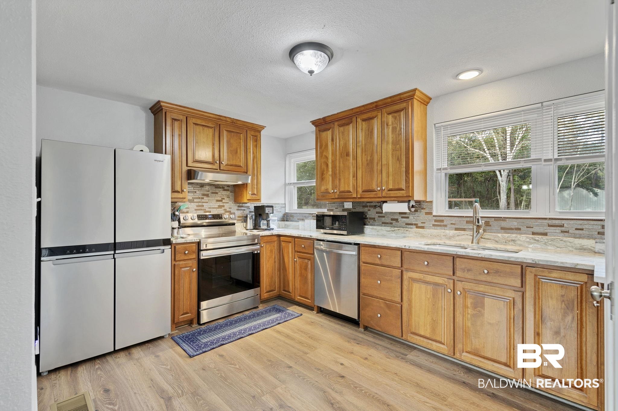 4690 Lott Road Eight Mile, AL 36613 - Photo 17 of 45 Kitchen featuring tasteful backsplash, sink, light stone counters, stainless steel appliances, and light wood-type flooring