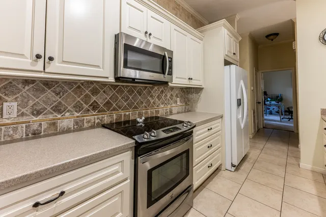 a kitchen with stainless steel appliances granite countertop white cabinets and stove