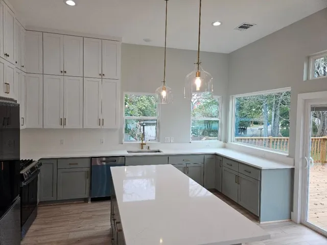 a kitchen with kitchen island granite countertop a stove a sink a counter space and windows