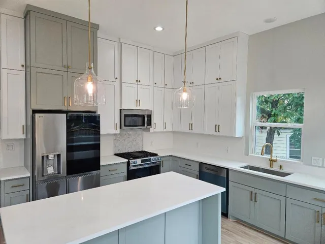 a kitchen with stainless steel appliances a sink a stove a refrigerator a center island and a window