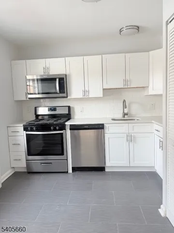 a kitchen with white cabinets and stainless steel appliances