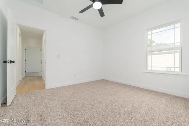 an empty room with a window and a ceiling fan