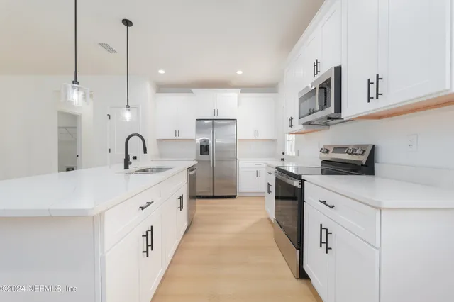 a kitchen with white cabinets appliances and a sink