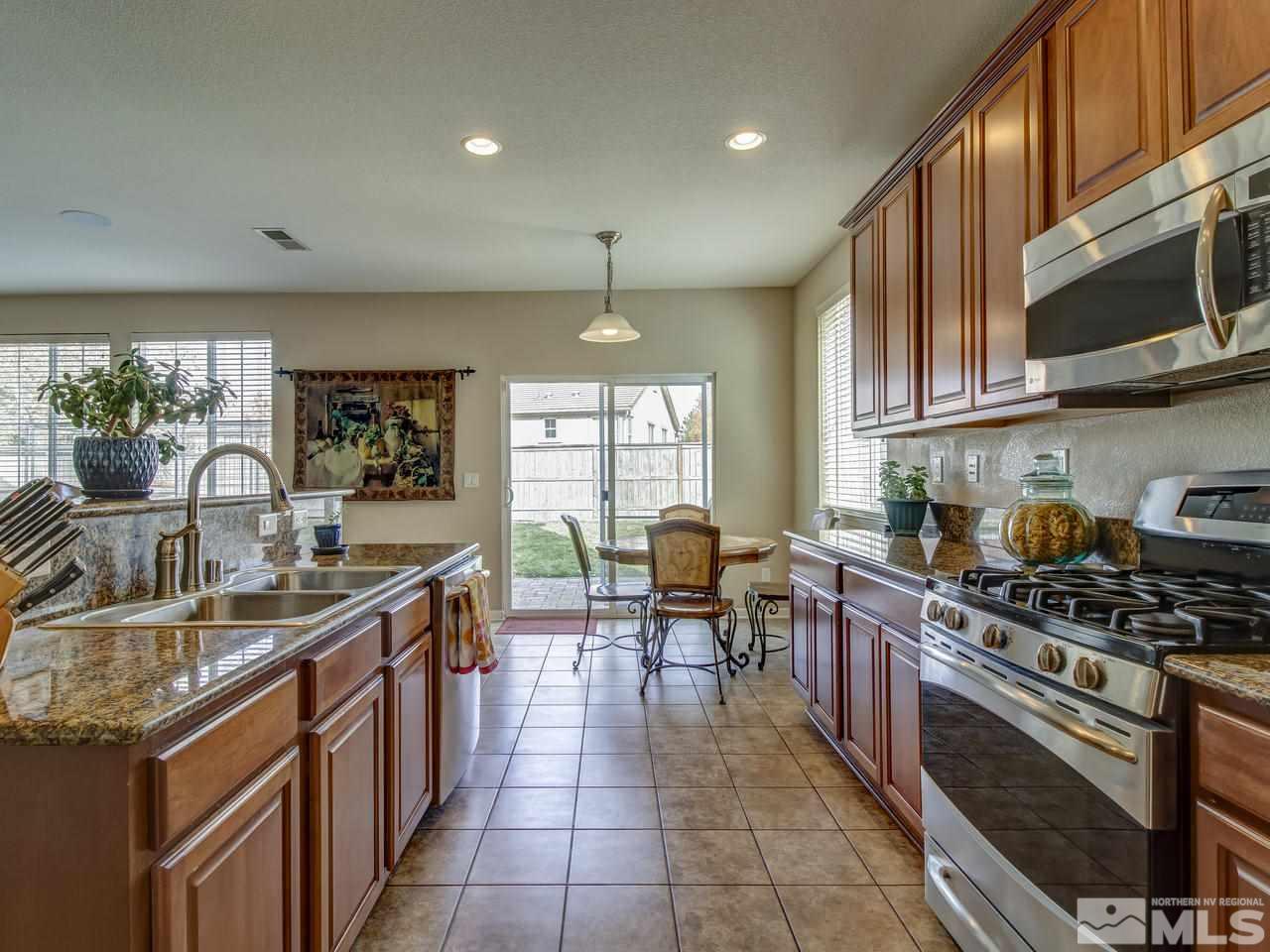 555 Little Sorrel Court Reno, NV 89521 - Photo 2 of 25 a kitchen with stainless steel appliances granite countertop a stove a sink dishwasher a microwave oven and a dining table with wooden cabinet
