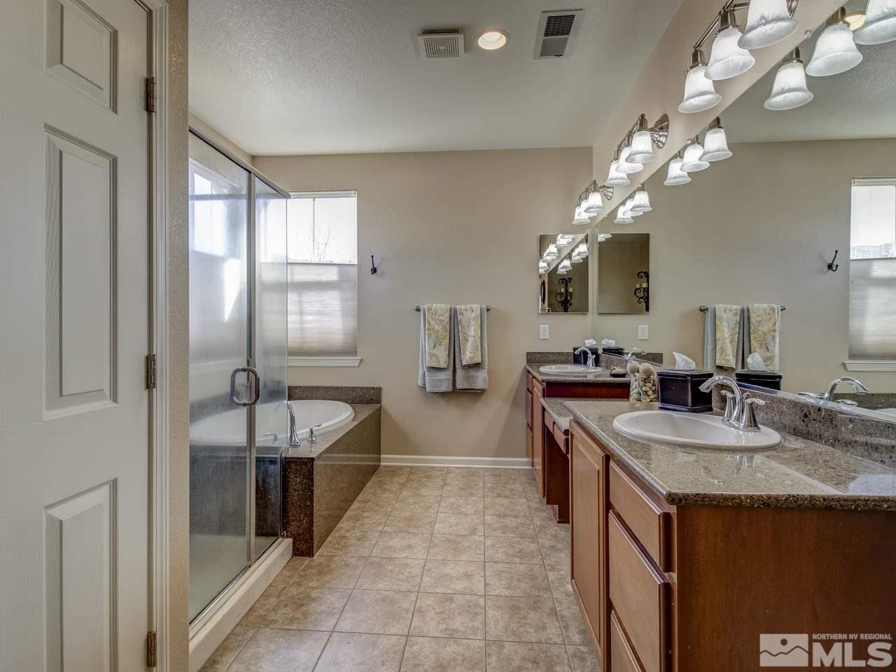 555 Little Sorrel Court Reno, NV 89521 - Photo 23 of 25 a spacious bathroom with a granite countertop sink a large mirror and a bathtub