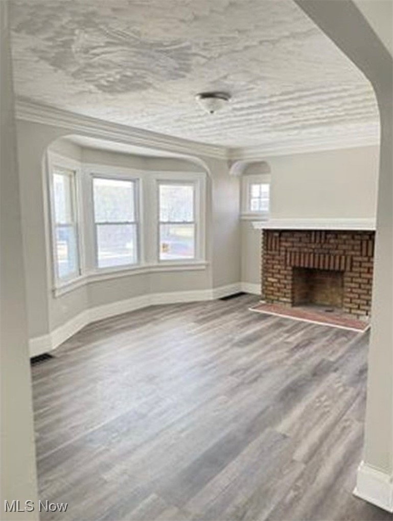 1743 Algonac Road Cleveland, OH 44112 - Photo 12 of 19 Unfurnished living room with arched walkways, ornamental molding, dark wood-style flooring, and a fireplace