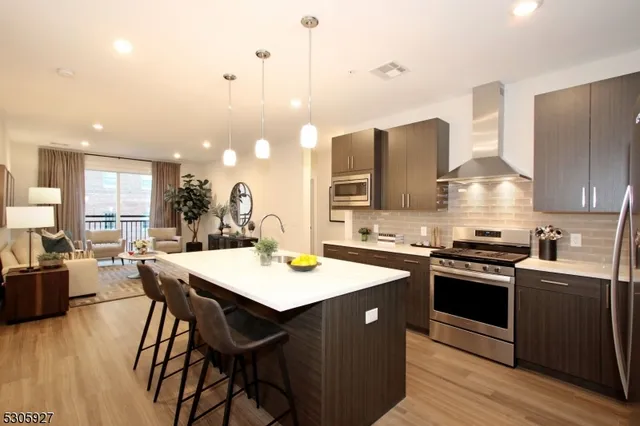 a kitchen with stainless steel appliances granite countertop a stove a sink dishwasher and a refrigerator with wooden floor