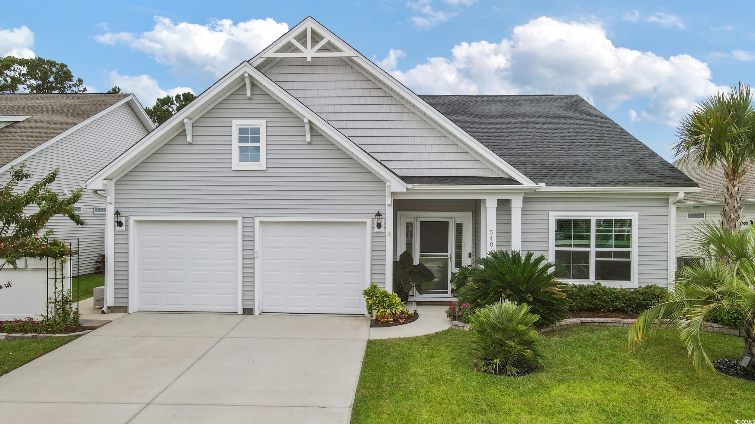 View of front facade with a garage, concrete driveway, a front yard, and roof with shingles