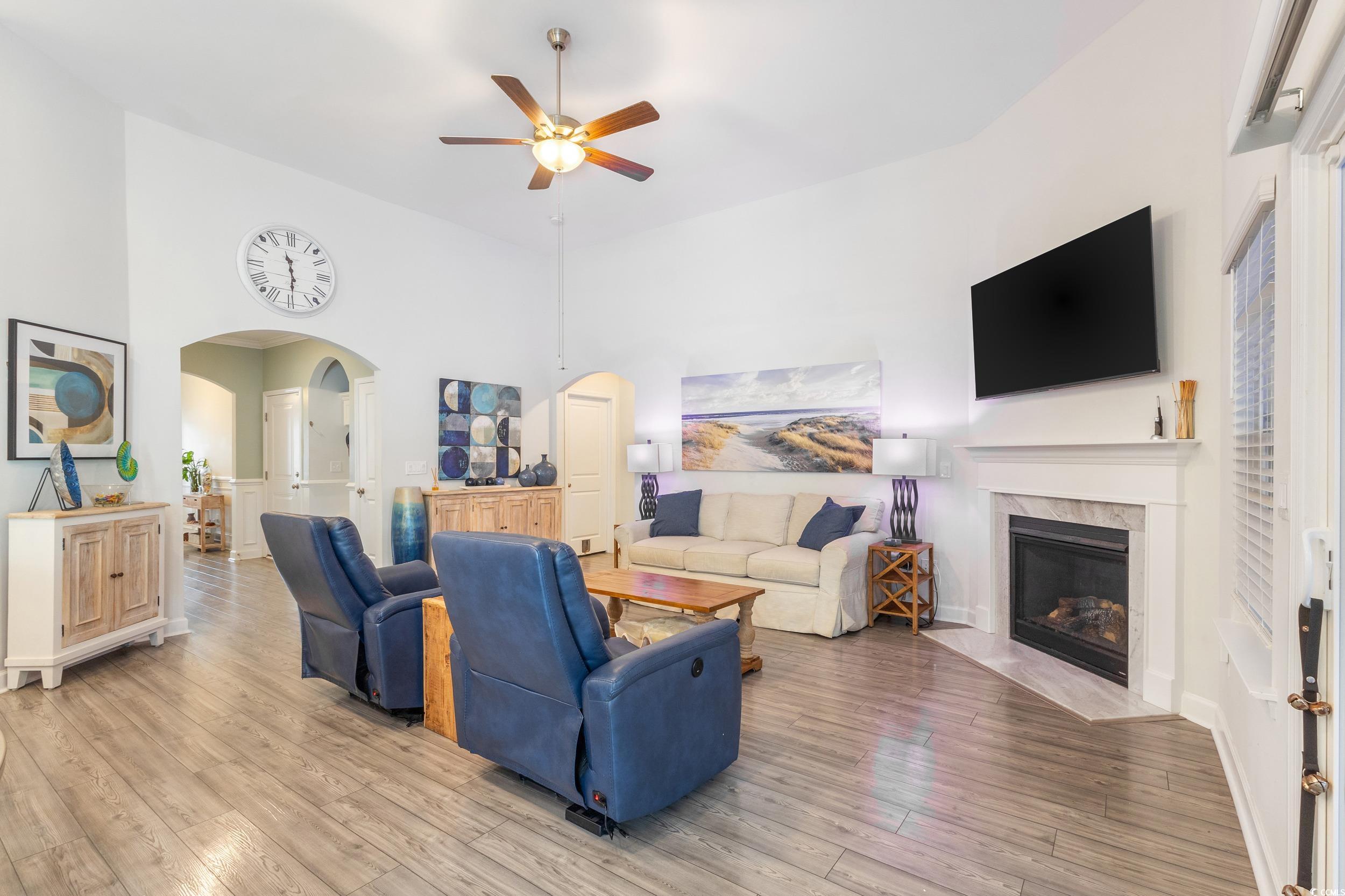 540 Canborough Lane Murrells Inlet, SC 29576 - Photo 11 of 40 Living room featuring arched walkways, light wood finished floors, a ceiling fan, a tiled fireplace, and a towering ceiling