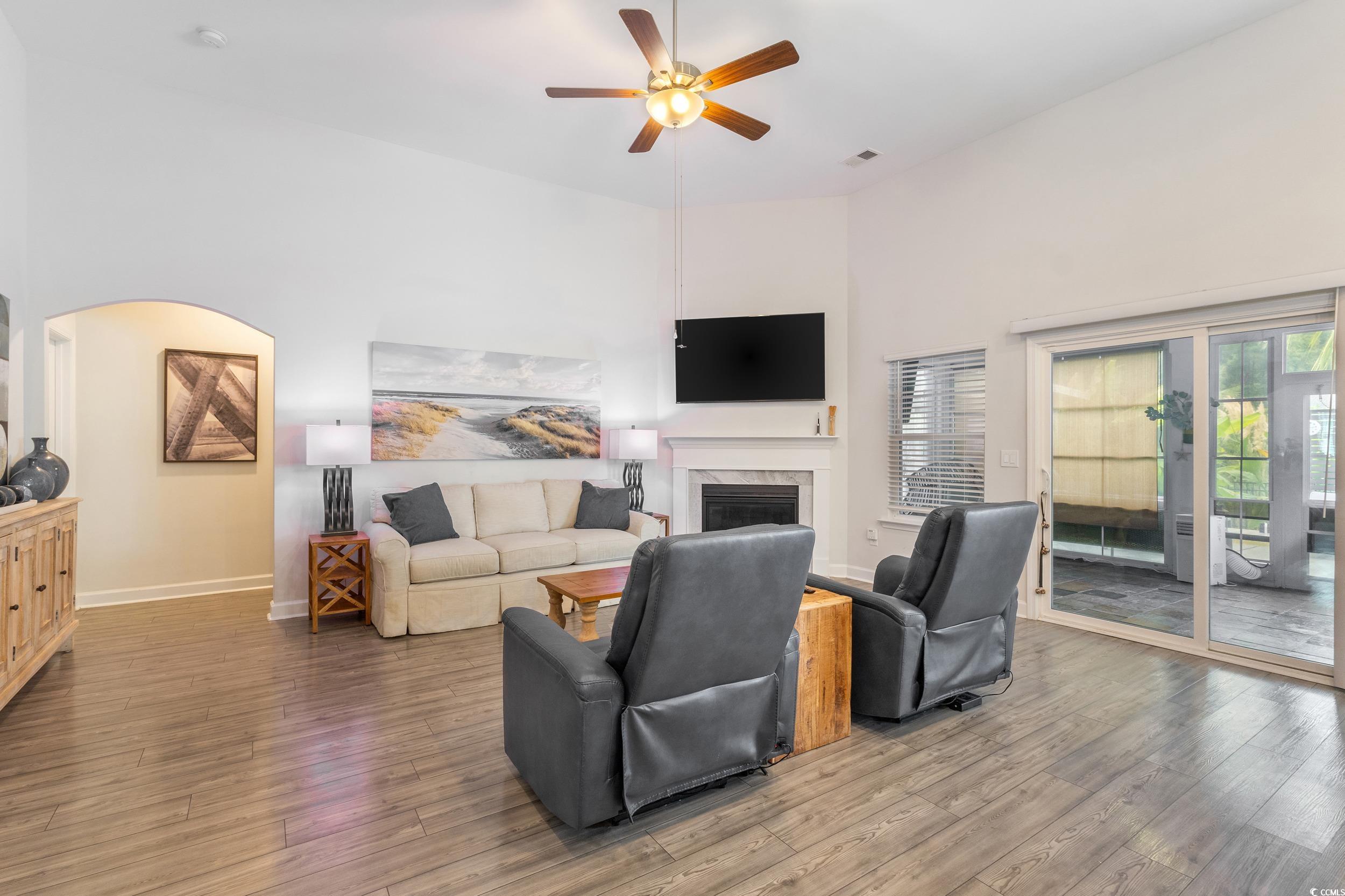 540 Canborough Lane Murrells Inlet, SC 29576 - Photo 12 of 40 Living room with a towering ceiling, wood finished floors, a fireplace, a ceiling fan, and arched walkways