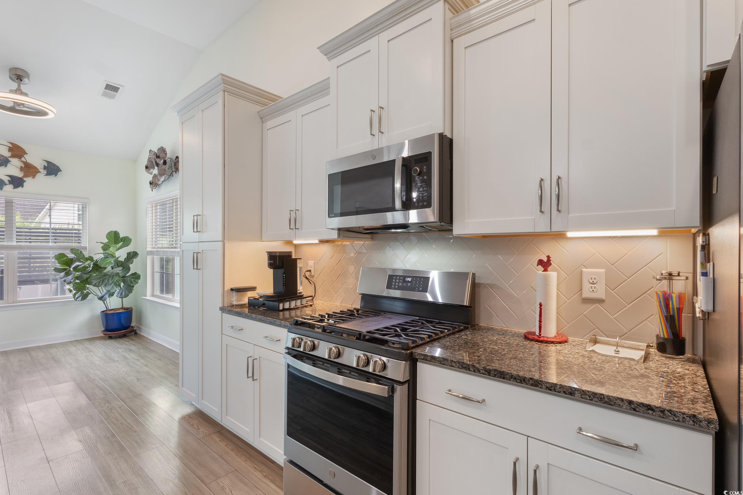 540 Canborough Lane Murrells Inlet, SC 29576 - Photo 15 of 40 Kitchen with appliances with stainless steel finishes, tasteful backsplash, dark stone counters, white cabinetry, and lofted ceiling