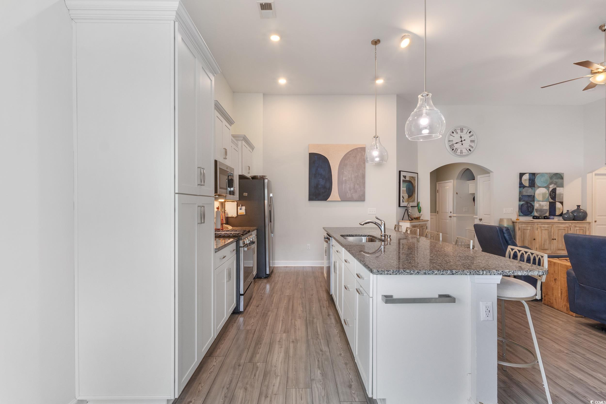 540 Canborough Lane Murrells Inlet, SC 29576 - Photo 39 of 40 Kitchen featuring a breakfast bar, open floor plan, white cabinets, arched walkways, and dark stone countertops