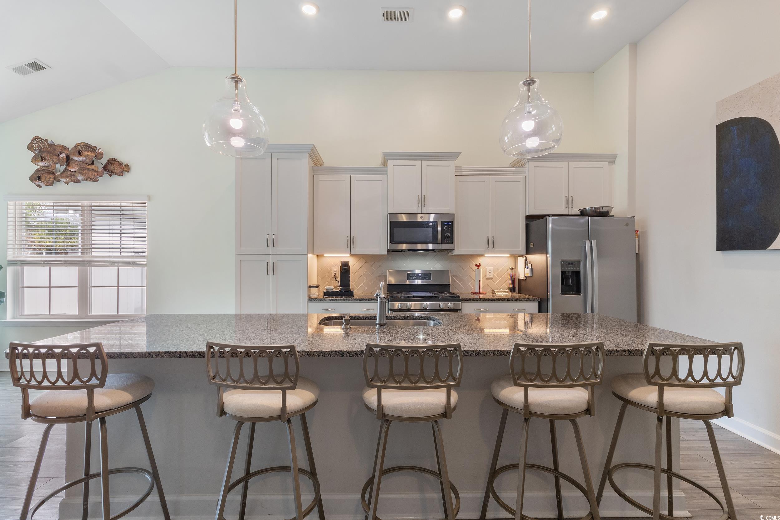 540 Canborough Lane Murrells Inlet, SC 29576 - Photo 18 of 40 Kitchen featuring light wood-style floors, tasteful backsplash, stainless steel appliances, dark stone counters, and a large island with sink