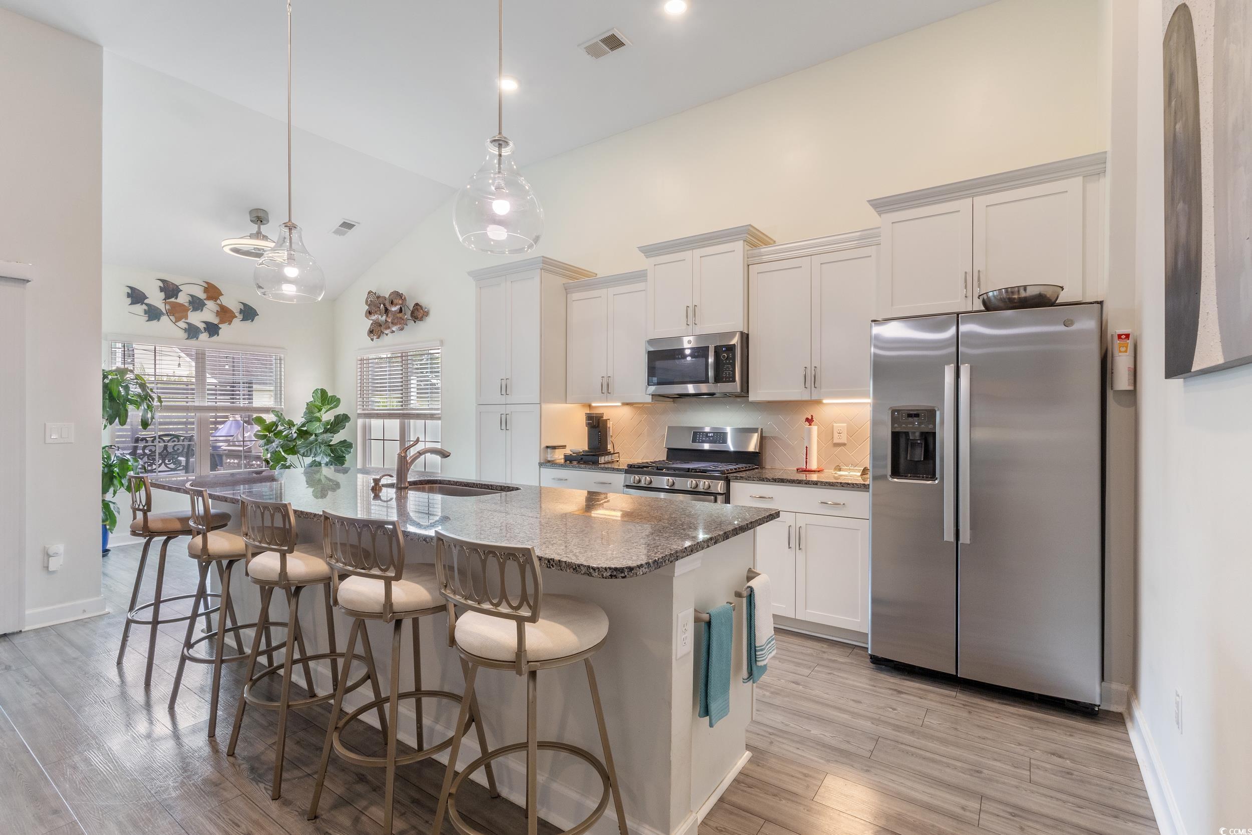540 Canborough Lane Murrells Inlet, SC 29576 - Photo 19 of 40 Kitchen with stainless steel appliances, dark stone countertops, a breakfast bar area, tasteful backsplash, and pendant lighting