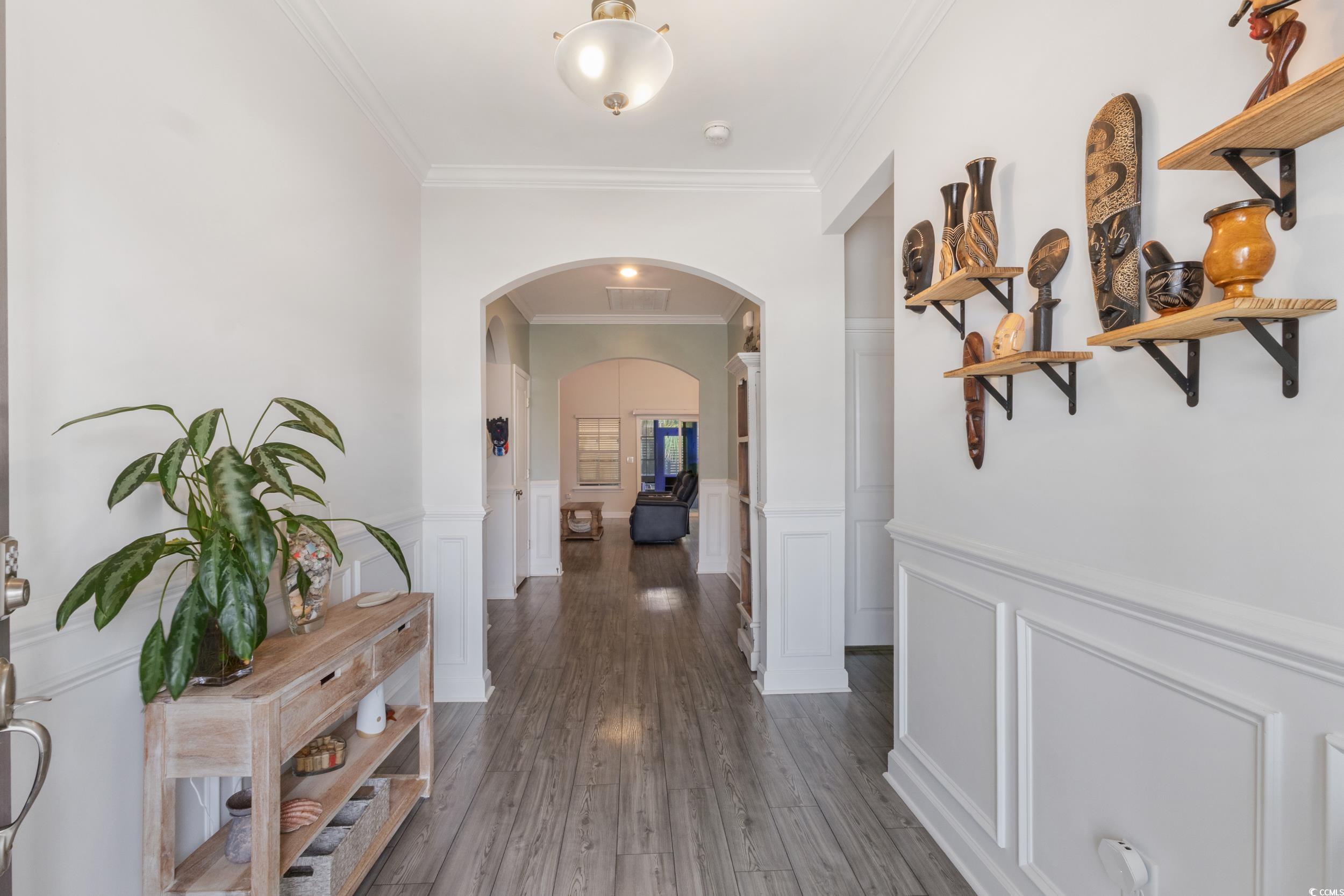 540 Canborough Lane Murrells Inlet, SC 29576 - Photo 7 of 40 Corridor with arched walkways, ornamental molding, dark wood-style flooring, wainscoting, and a decorative wall