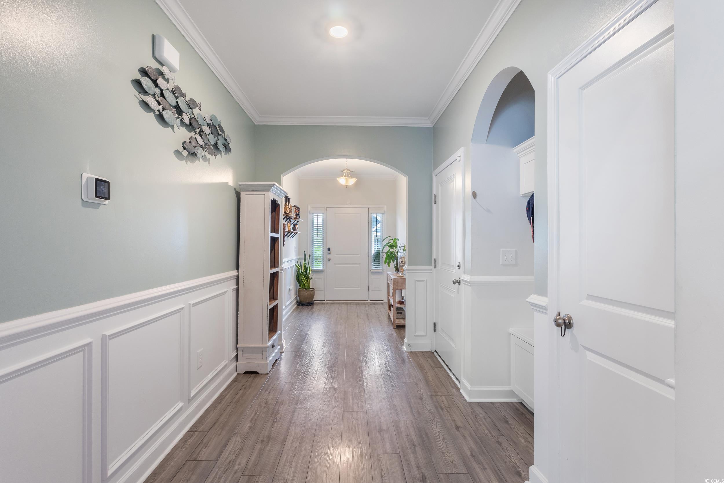 540 Canborough Lane Murrells Inlet, SC 29576 - Photo 8 of 40 Hallway with arched walkways, crown molding, wood finished floors, a wainscoted wall, and a decorative wall