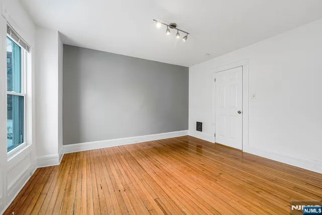 a view of empty room with wooden floor and fan
