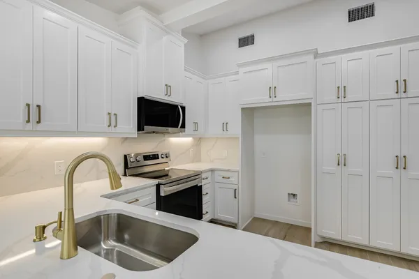 a kitchen with stainless steel appliances granite countertop a sink a stove and a refrigerator with white cabinets