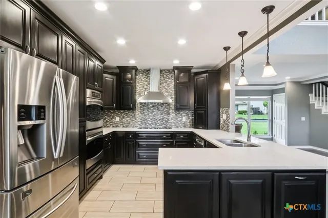 a kitchen with stainless steel appliances granite countertop a sink a stove and a refrigerator