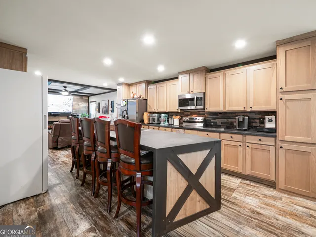 a kitchen with stainless steel appliances kitchen island granite countertop a dining table chairs and granite counter tops