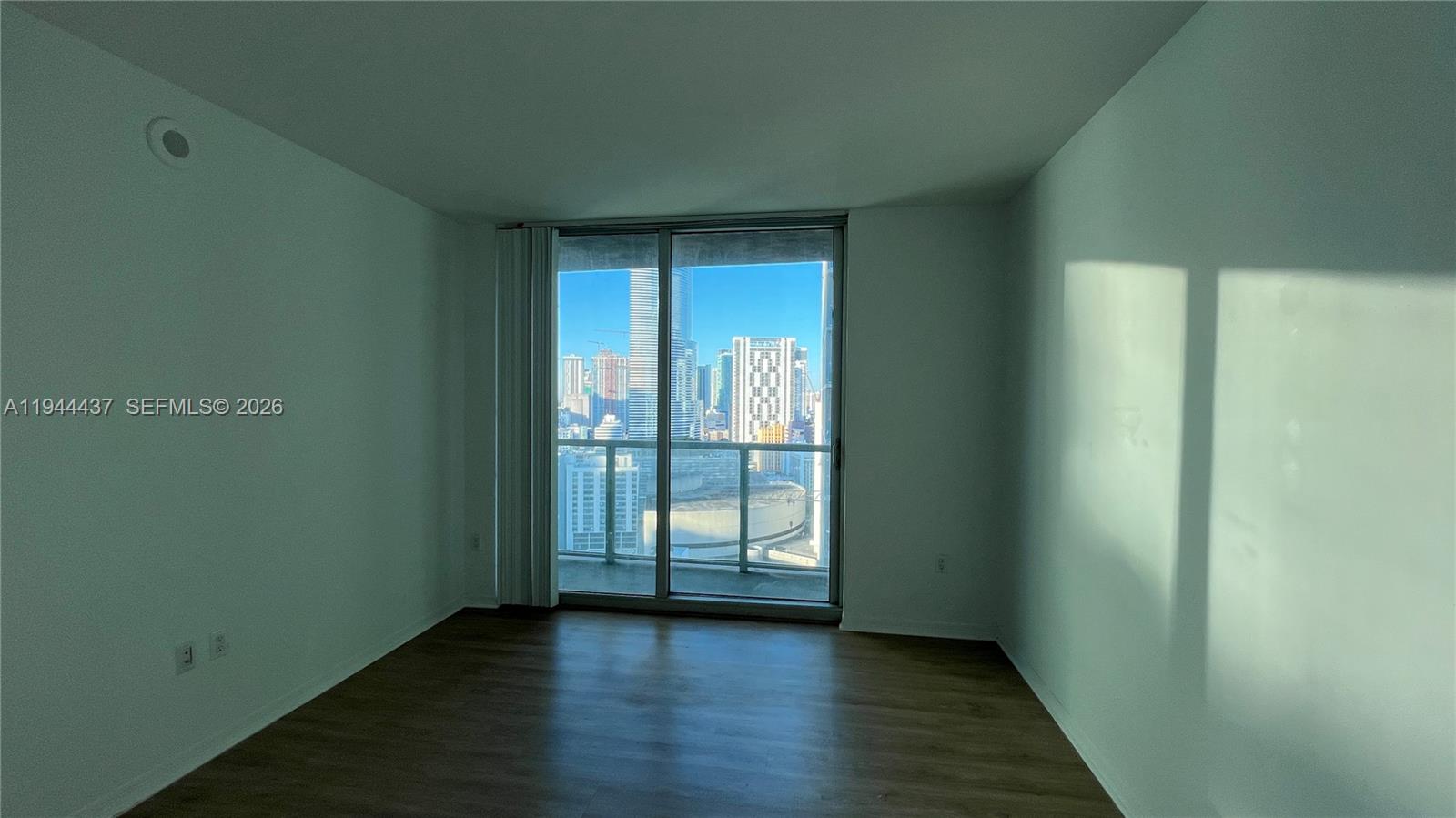 55 Southeast 6th Street, Unit 2601 Miami, FL 33131 - Photo 13 of 46 a view of an empty room with wooden floor and a window