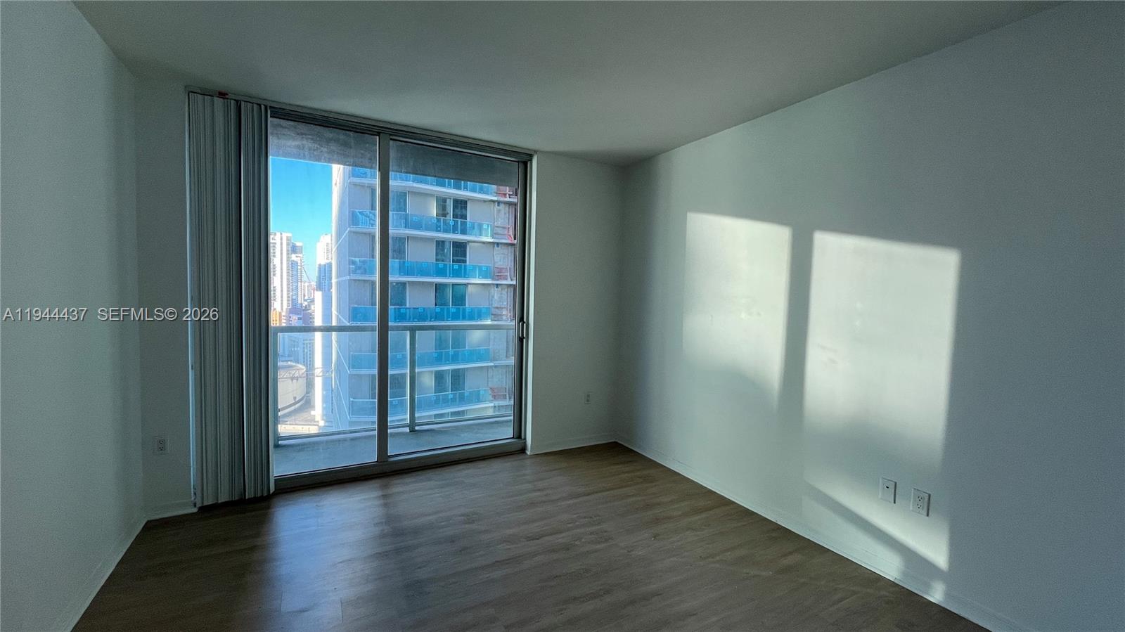 55 Southeast 6th Street, Unit 2601 Miami, FL 33131 - Photo 14 of 46 an empty room with wooden floor and windows