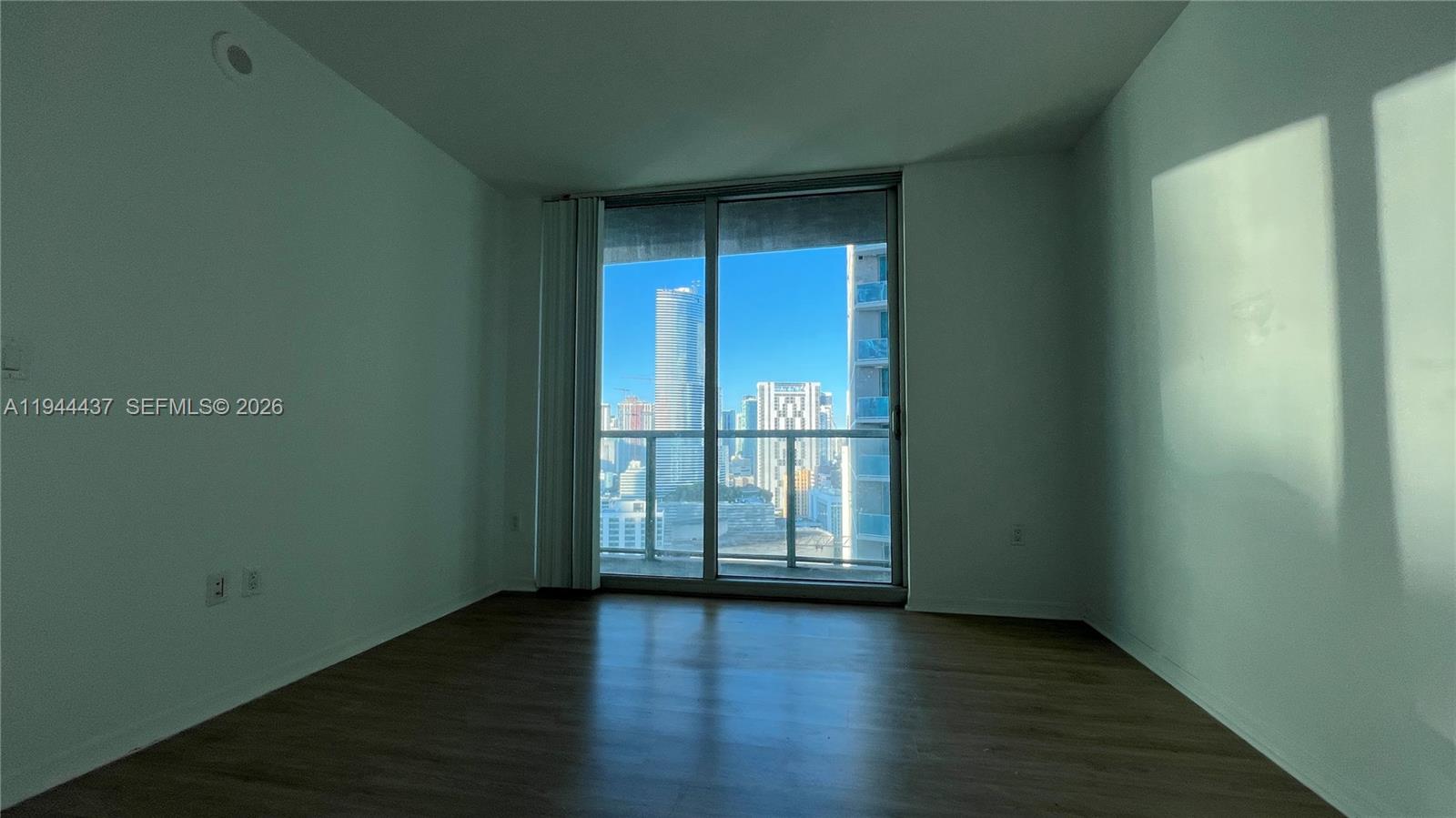 55 Southeast 6th Street, Unit 2601 Miami, FL 33131 - Photo 17 of 46 an empty room with wooden floor and sliding door