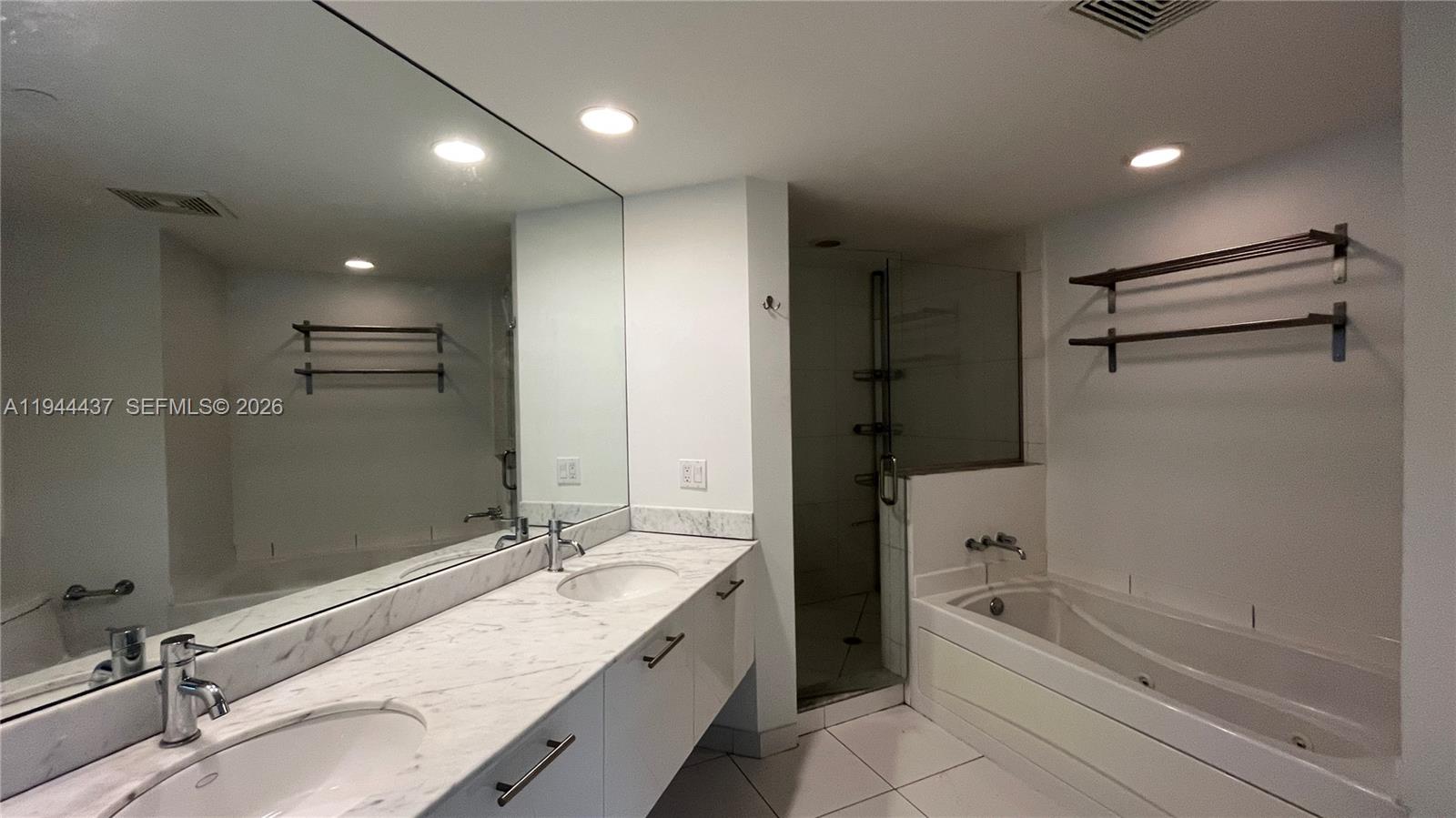 55 Southeast 6th Street, Unit 2601 Miami, FL 33131 - Photo 18 of 46 a bathroom with a granite countertop sink a mirror and a bathtub