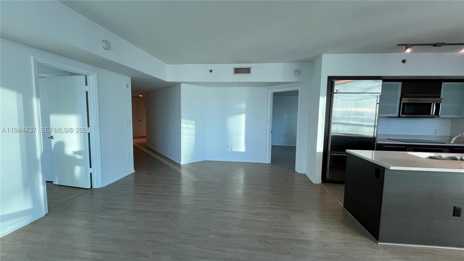 55 Southeast 6th Street, Unit 2601 Miami, FL 33131 - Photo 6 of 46 a view of a refrigerator in kitchen and an empty room with wooden floor