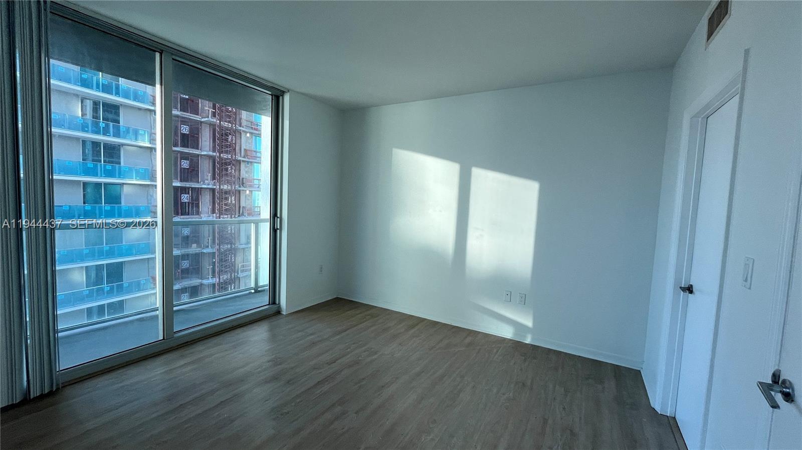 55 Southeast 6th Street, Unit 2601 Miami, FL 33131 - Photo 10 of 46 a view of an empty room with wooden floor and a window