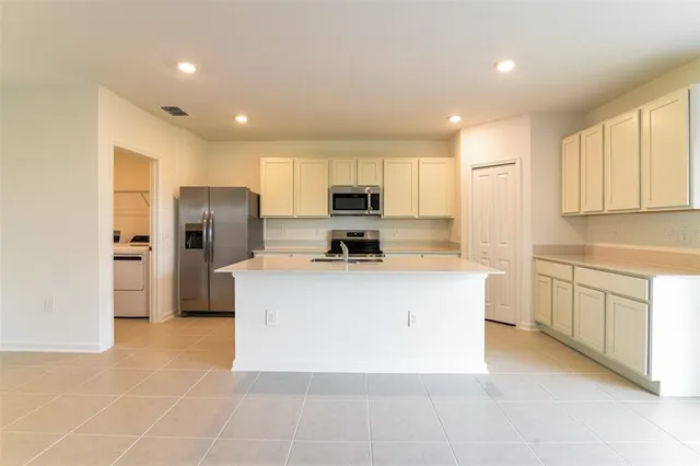 a large kitchen with stainless steel appliances granite countertop a stove a refrigerator a sink a microwave and island