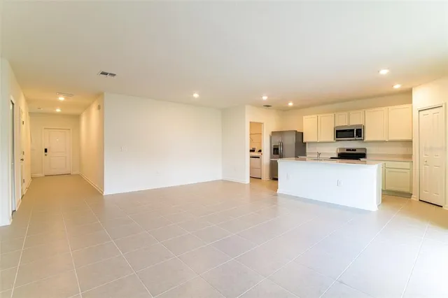 a view of kitchen with kitchen island a sink a stove a refrigerator and white cabinets