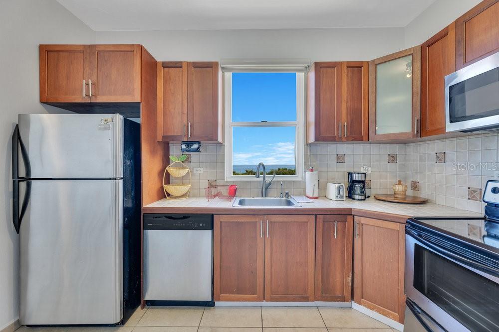 413 Camino Carretas, Unit A7 Rincon, Rincón 00677 - Photo 8 of 23 a kitchen with a refrigerator sink and cabinets