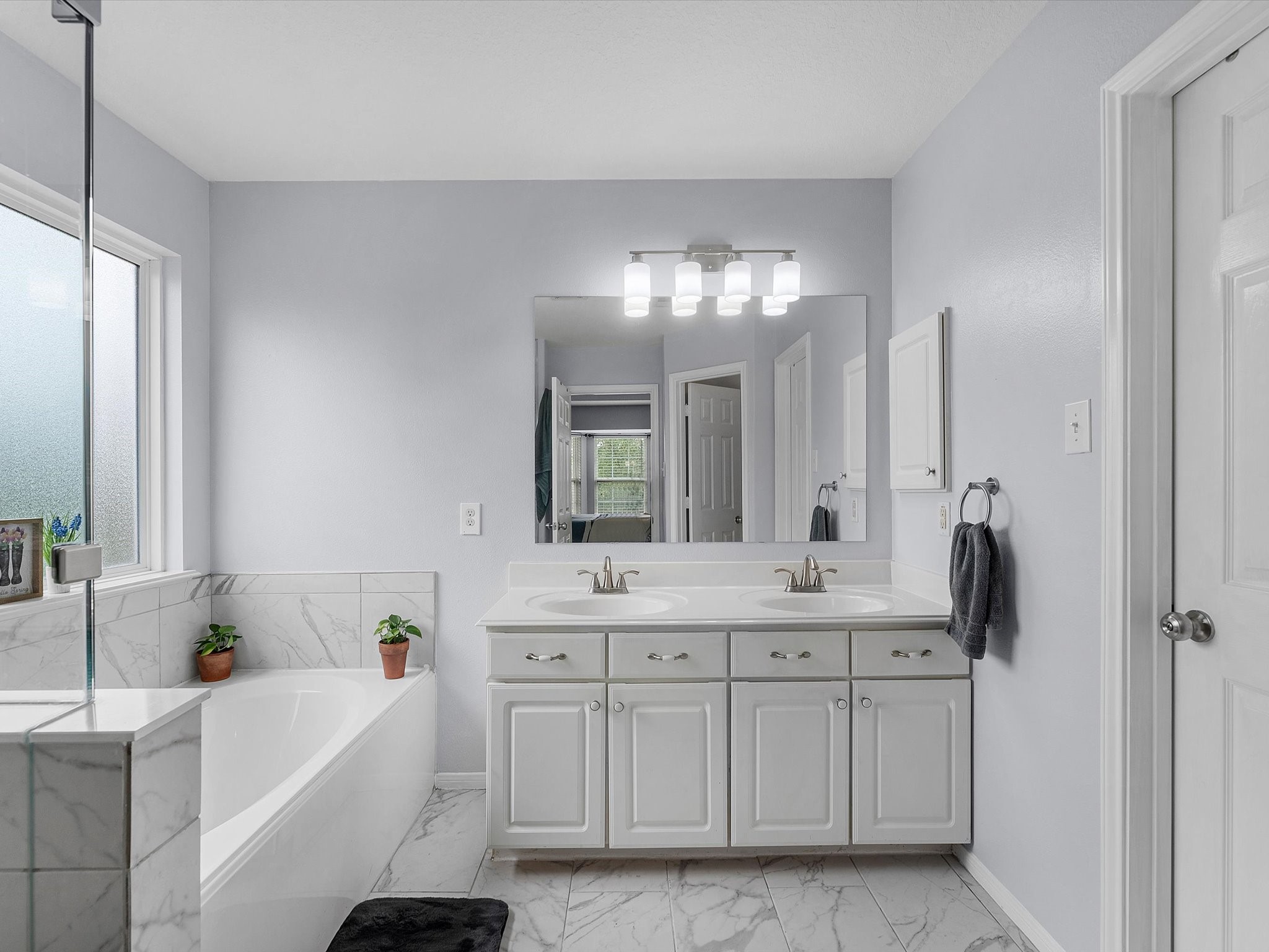 22422 Lamaster Lane Spring, TX 77373 - Photo 21 of 35 Primary bathroom features a modern, bright design with a large soaking bathtub, separate shower and dual vanity sinks.