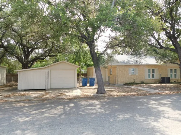 a view of a house with a large tree and a yard