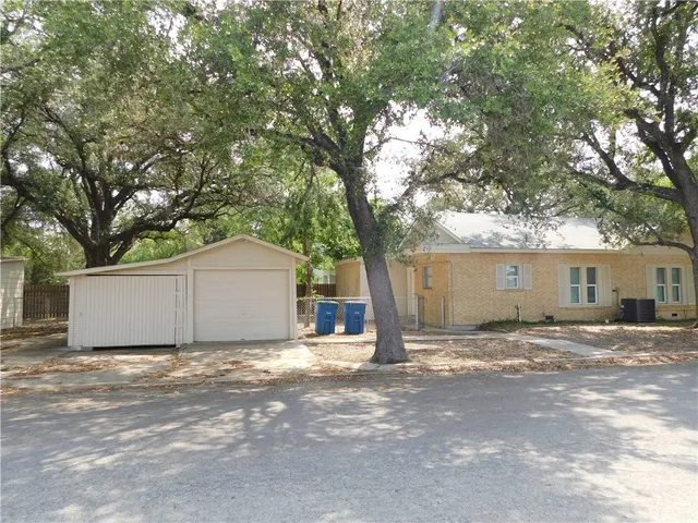 a view of a house with a large tree and a yard