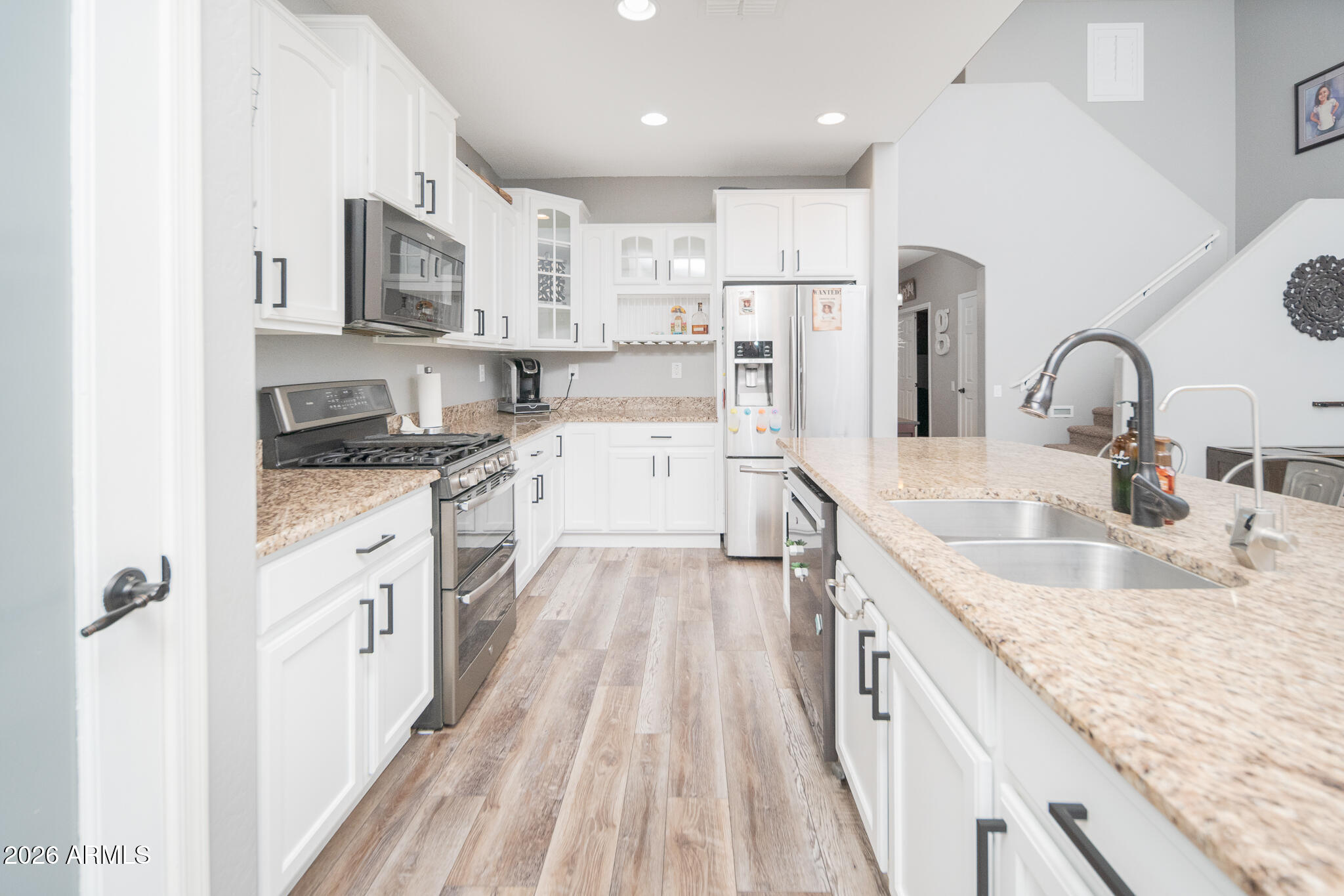 10789 West Yearling Road Peoria, AZ 85383 - Photo 5 of 35 a large kitchen with granite countertop a sink stove refrigerator and white cabinets with wooden floor