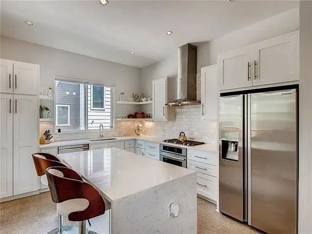 a kitchen with a refrigerator a stove a sink and chairs