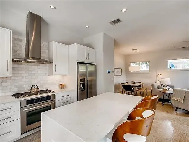 a kitchen with stainless steel appliances a stove a refrigerator a sink a stove and island