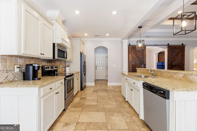 a kitchen with stainless steel appliances granite countertop white cabinets a refrigerator and a stove a sink