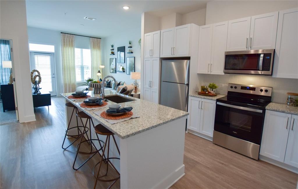 a kitchen with stainless steel appliances a kitchen island hardwood floor sink stove and microwave