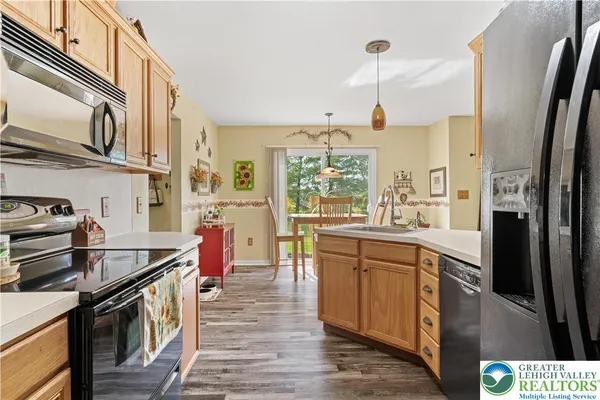 a kitchen with stainless steel appliances granite countertop a refrigerator a sink dishwasher a stove and a dining table with wooden floor